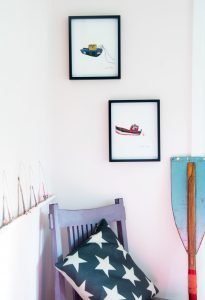 Two embroidered tugboat pictures with a row of scenes in arches on the shelf