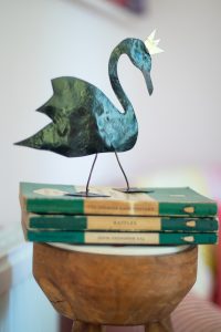 copper black sprayed swan in a crown sat on a pile of penguin books