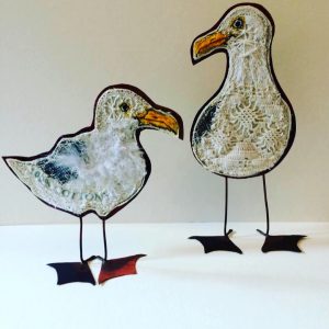 Two embroidered seagulls with copper bodies