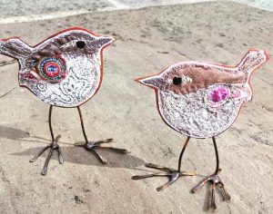 Two embroidered wrens with copper bodies