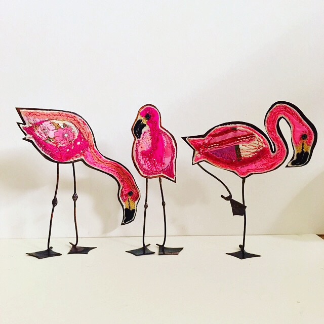 Three embroidered flamingoes with copper bodies
